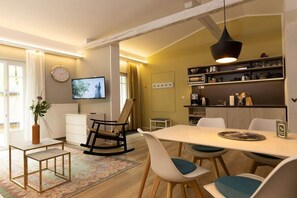 A modern living room with a dining area, a television, and a kitchen in the background. - Little Suite Apartment 3 (Dresden)