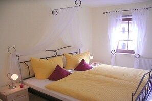 A bed with a canopy, bedside lamps, and a window with curtains. - Holiday apartment with 1 bedroom (Bad Schandau)