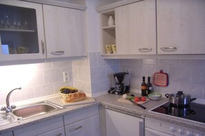 A kitchen with white cabinets, a sink, a coffee maker, and a stove. - Holiday apartment with 1 bedroom (Bad Schandau)