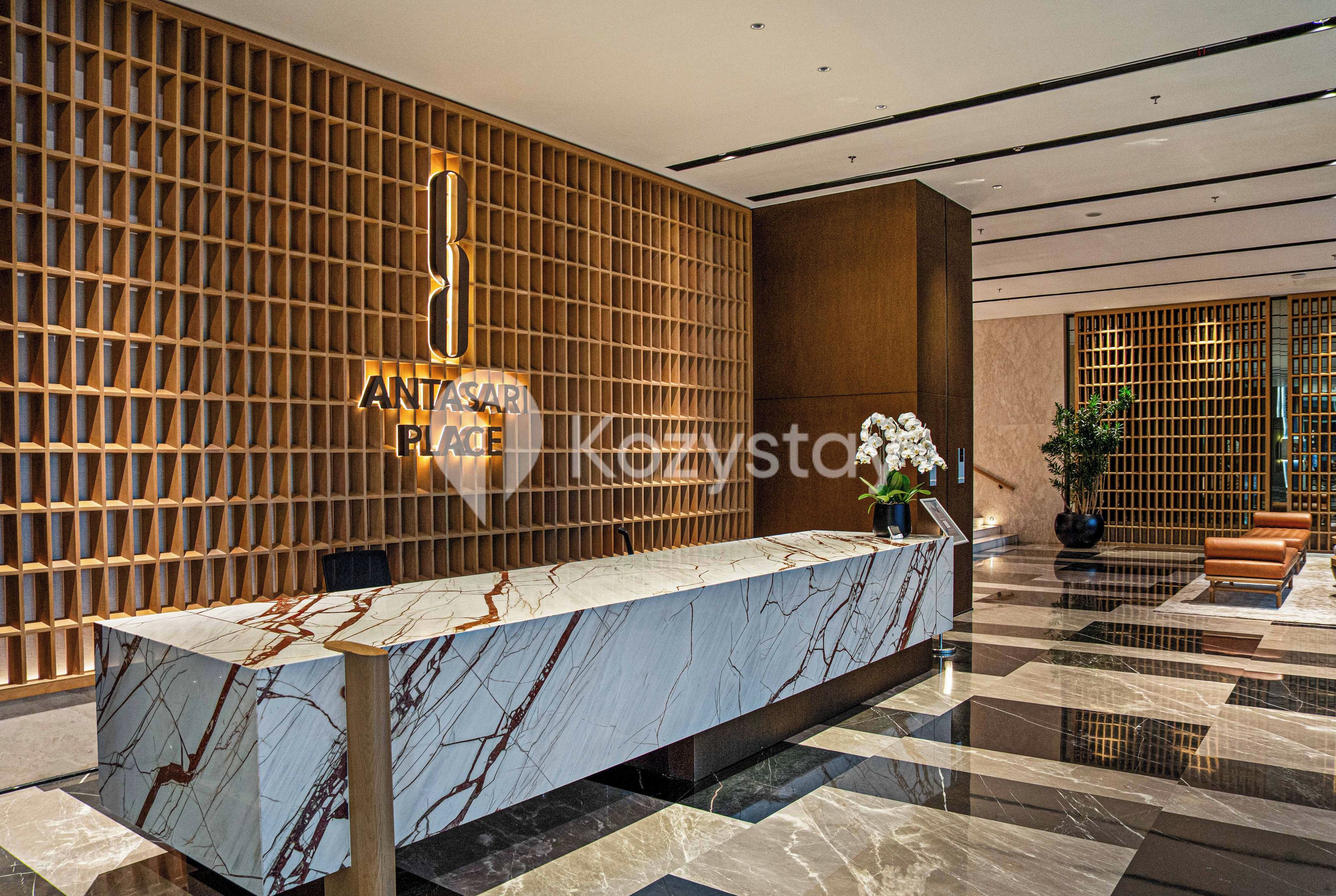 A reception area with a marble reception desk, wooden panel wall, and a potted plant.