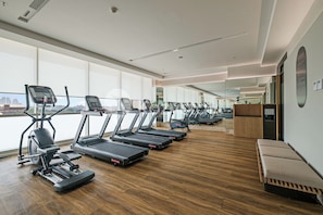 A modern gym with multiple treadmills, a rowing machine, and a bench. - Skora by Kozystay - Cilandak (South Jakarta)