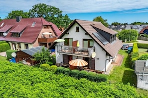 Ein Wohnhaus mit geneigtem Dach, einem Balkon mit Geländer und einer Satellitenschüssel.