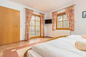 Ein Schlafzimmer mit Bett, Vorhängen, einem Fernseher und einer Heizung.