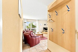 Ein modernes Wohnzimmer mit einem roten Ledersofa, einer Holzkabine mit Haken und einem Fernseher.