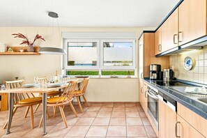 Eine moderne Küche mit Essbereich, großen Fenstern und Blick auf Grünflächen.