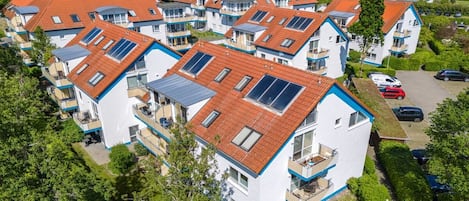 A residential area with multiple two-story houses featuring red-tiled roofs and solar panels.