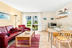 Ein modernes Wohnzimmer mit einem roten Ledersofa, einem Holztisch und einem Essbereich inklusive Tisch und Stühlen.