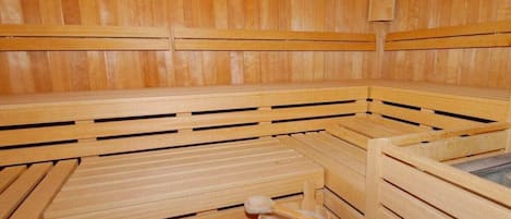 Uma sauna com bancos de madeira e um balde de madeira.