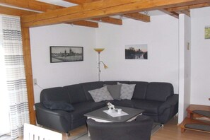 Ein modernes Wohnzimmer mit einem dunkelgrauen Sofa, einem Couchtisch und zwei Bildern an der Wand.