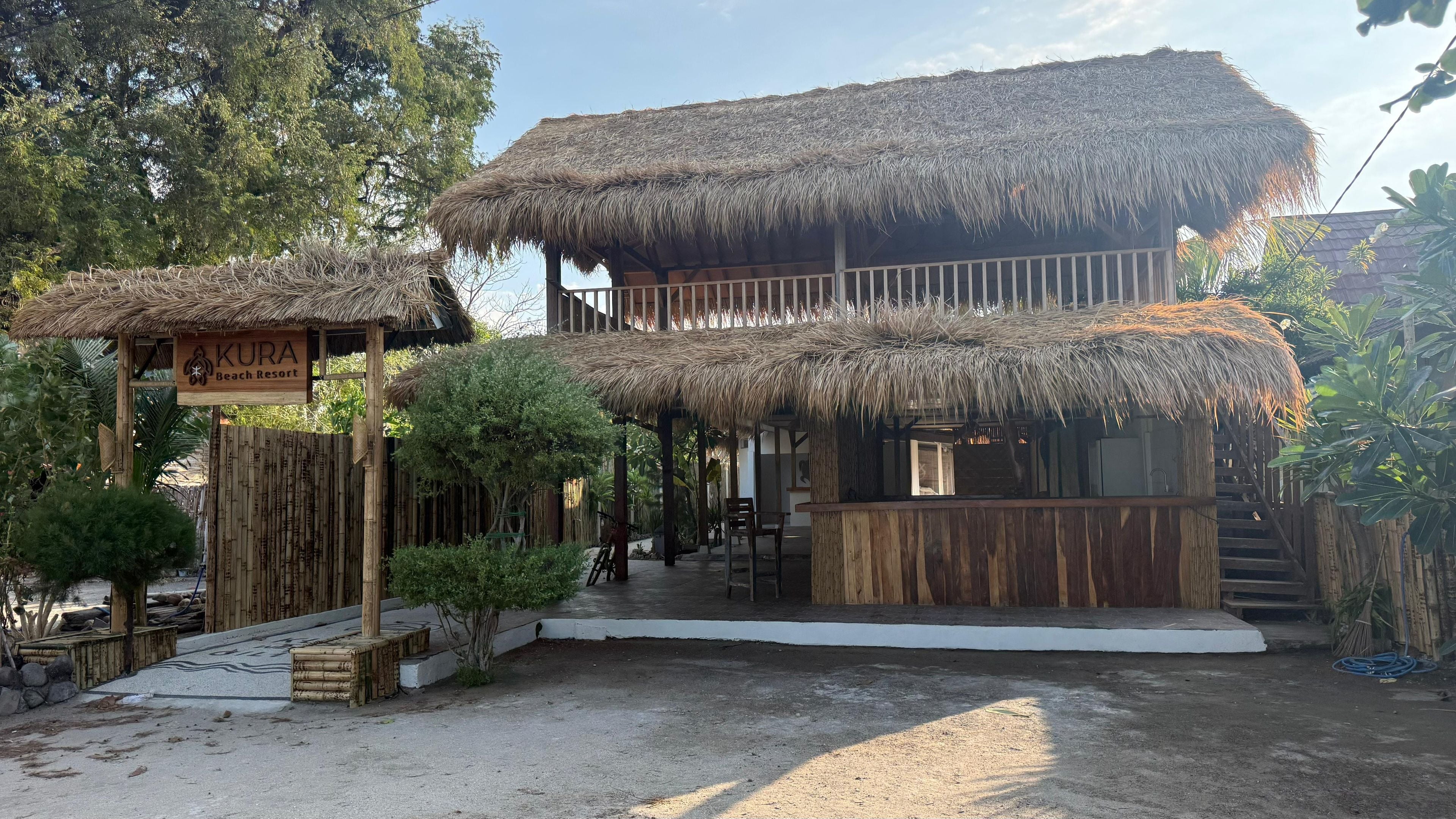 A two-story building with thatched roofs and a wooden fence.