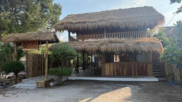 A two-story building with thatched roofs and a wooden fence.