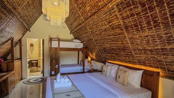 A room with a high ceiling, a large bed, a chandelier, and a wooden ceiling.