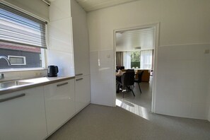 A modern kitchen with a window, a coffee maker, and a dining area with chairs and a table. - Holiday home with 3 bedrooms (Zoutelande)