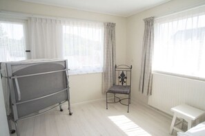 A room with a metal bed frame, a small white stool, and a chair with a cushion. - Holiday home with 3 bedrooms (Zoutelande)