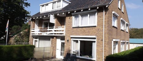 A two-story house with a balcony, a garage, and a well-maintained lawn.