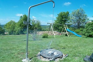 A backyard with a swing set, a slide, and a grill. - "Vogelsberg Holiday Magic" (Herchenhain)