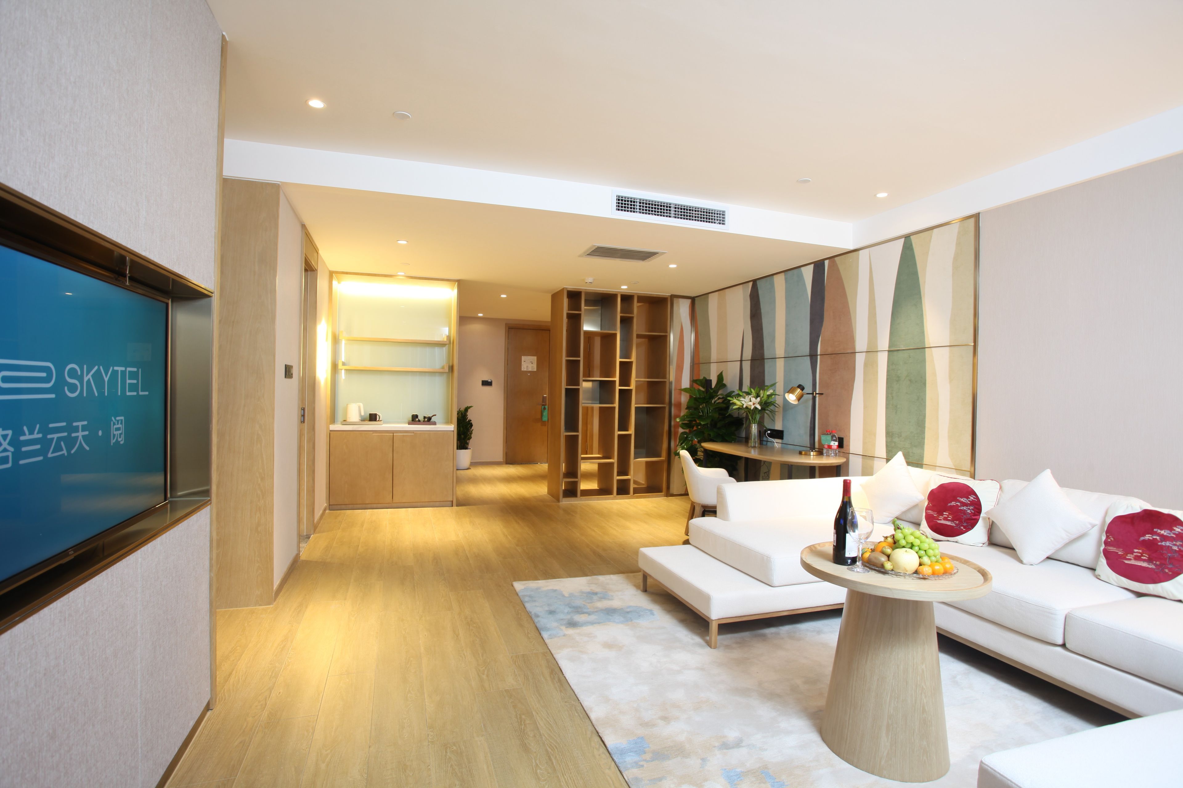 A modern hotel lobby with a reception desk, seating area, and a large screen displaying the hotel name.