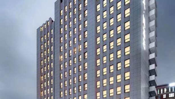 Un hotel moderno de gran altura, con varios pisos, una entrada destacada y una fachada bien iluminada.