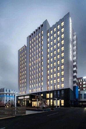 A high-rise hotel with multiple floors, a prominent entrance, and a well-lit facade. - The Skytel Beijing Aoyu (Daxing)