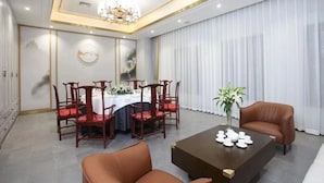 Uma sala de jantar com uma mesa redonda, cadeiras e uma mesinha de centro com xícaras de chá.