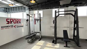 A gym with exercise equipment, a wall with motivational text, and large windows allowing natural light.