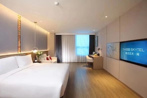 A hotel room with a large bed, a desk, a TV, and a view of the outdoors. - The Skytel Beijing Aoyu (Daxing)