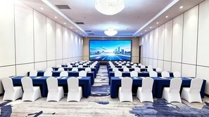 A conference room with rows of tables and chairs, a large screen at the front, and a chandelier. - The Skytel Beijing Aoyu (Daxing)