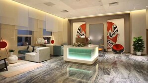 Um hall moderno com balcão de atendimento, área de estar e arte decorativa na parede.