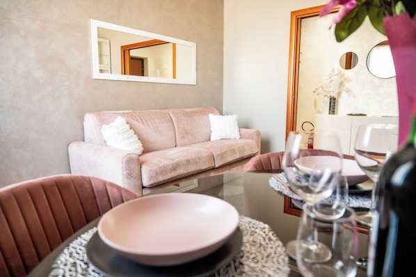 A modern living room with a sofa, dining table, chairs, and a glass-top coffee table. - Vrbo Property (Roma)