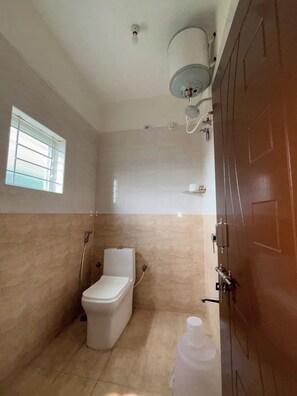 Casa de banho com sanita, chuveiro, janela e porta.