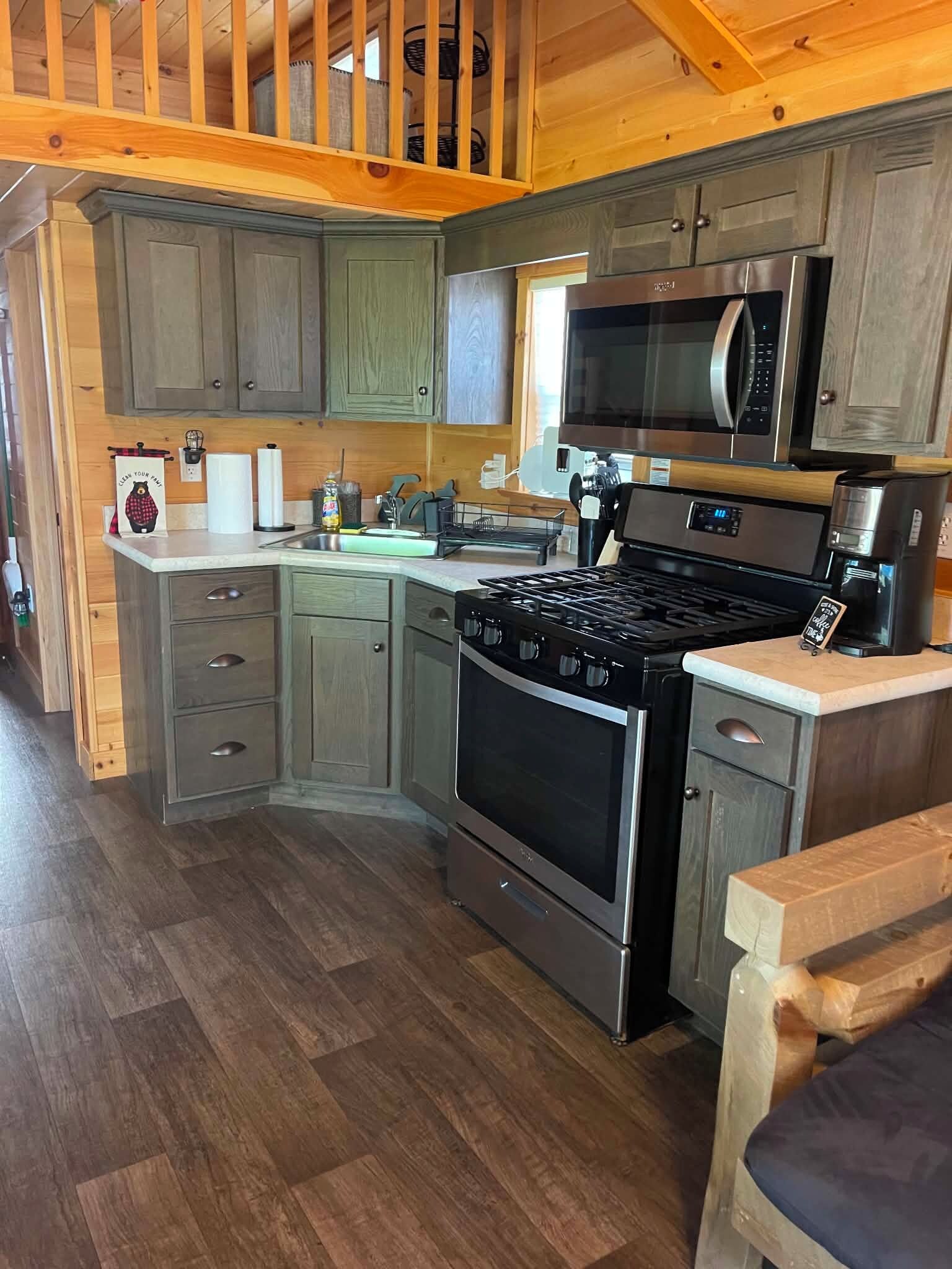 Een moderne keuken met houten kastjes, een rvs-fornuis en een magnetron.