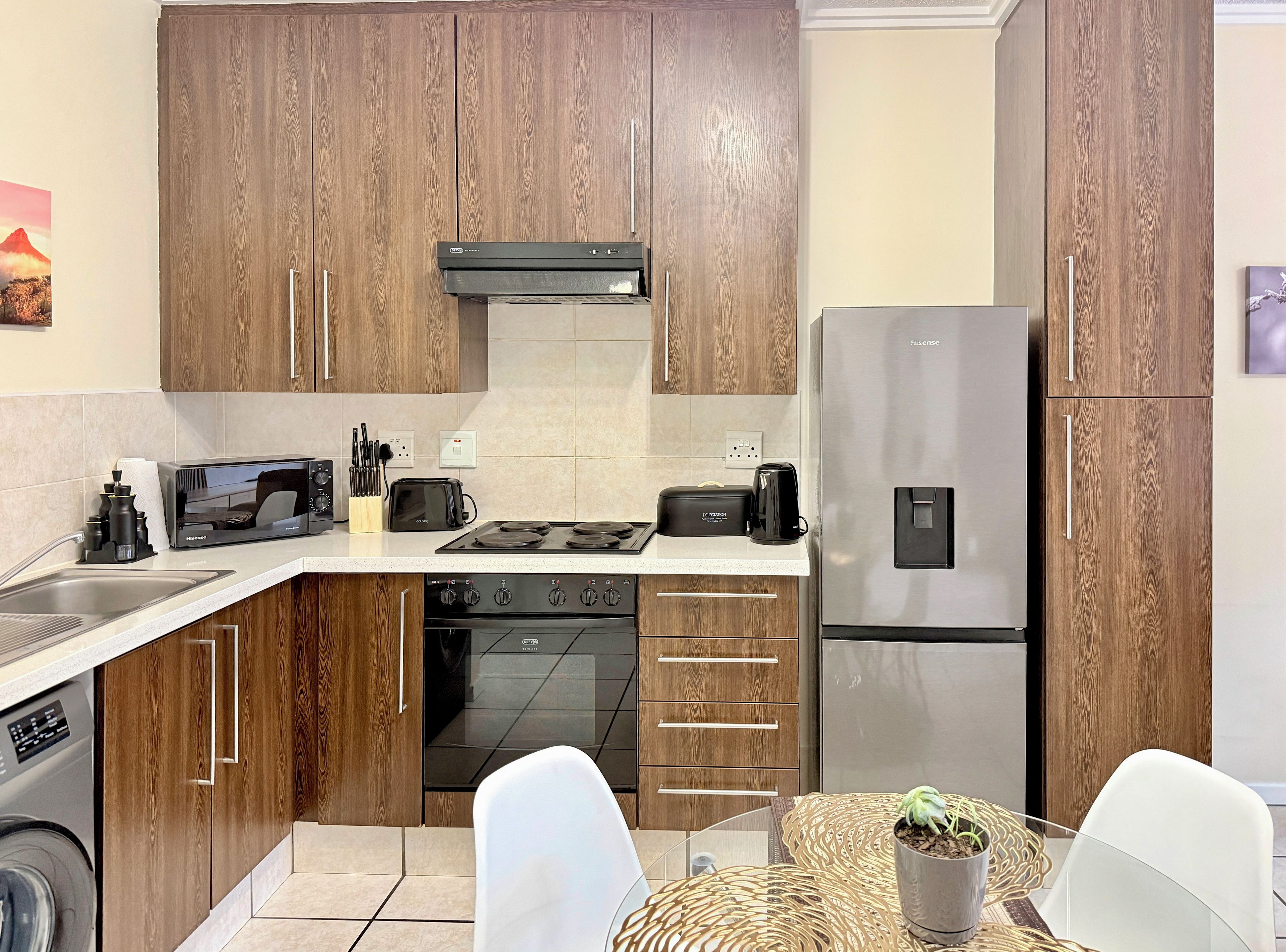 Una cucina moderna con mobili in legno, un frigorifero in acciaio inossidabile, un forno a microonde, un tostapane e un fornello.