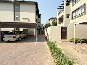 A residential building with a covered parking area and a narrow alleyway. - Marvelous 1-bedroom apartment in Sandton perfect for your stay (Sandton)