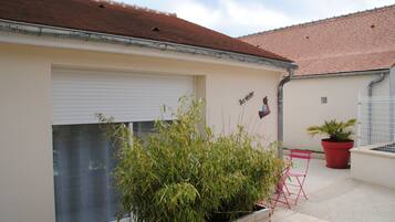 Un edificio residencial con puerta de garaje, una planta en maceta y una silla roja.