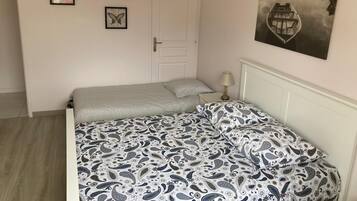 Un dormitorio con cama, una puerta, una lámpara y dos cuadros en la pared.
