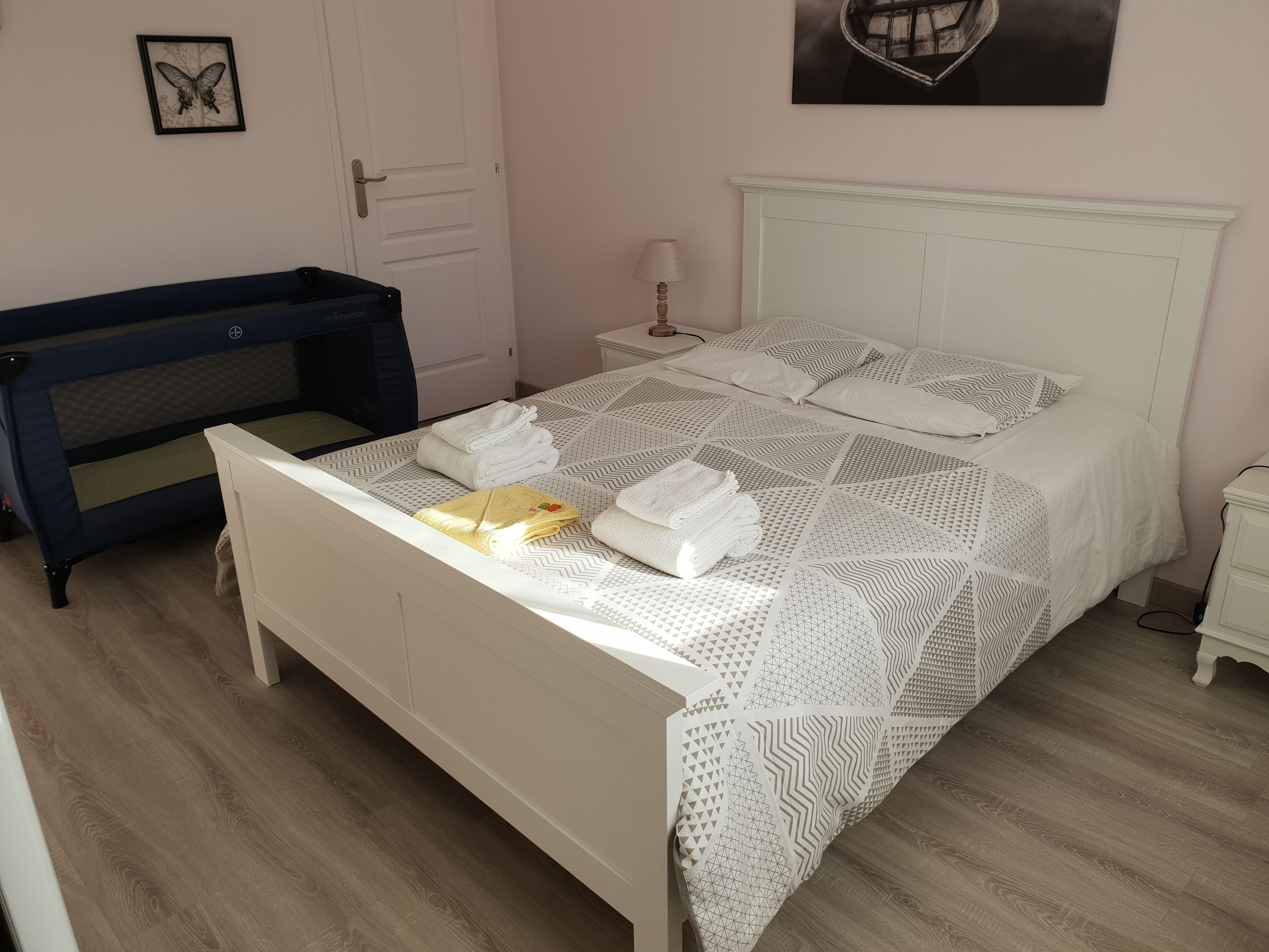 Un lit bien fait, avec une literie à motifs, une table de chevet avec une lampe, et un canapé bleu dans une pièce au plancher en bois.