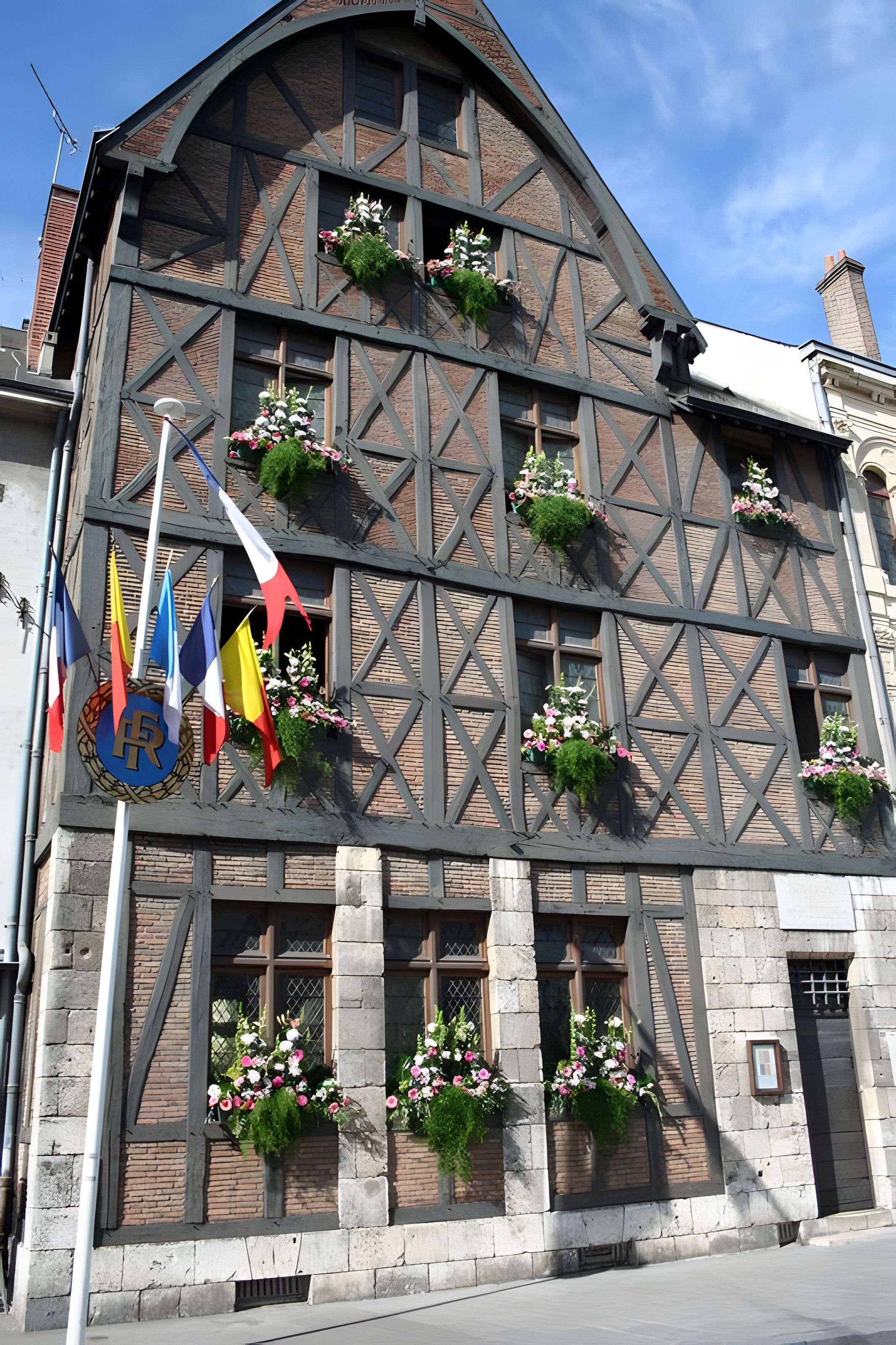 Um edifício em estilo enxaimel com caixas de flores nas janelas e bandeiras na fachada.