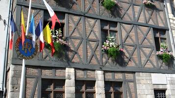 Un edificio con entramado de madera, con macetas de flores en los alféizares de las ventanas y banderas en la fachada.
