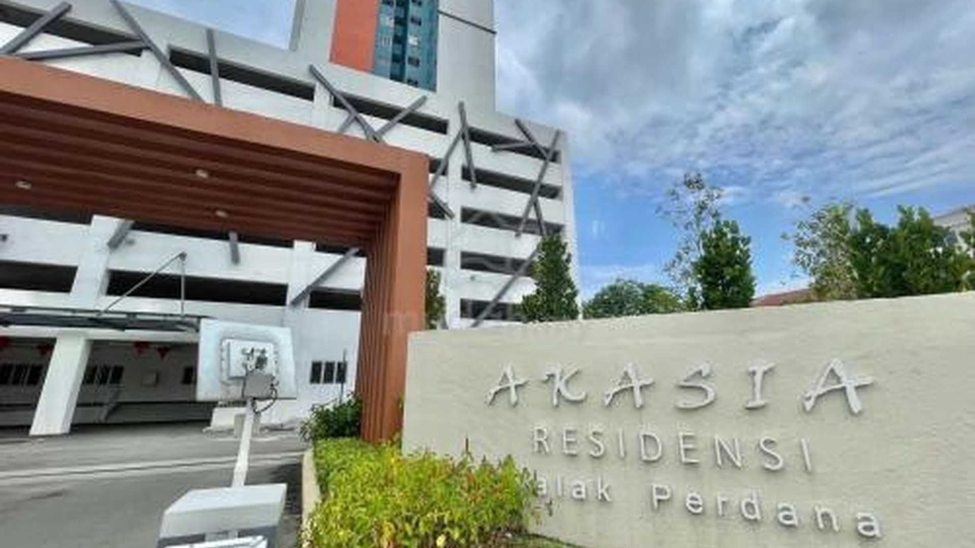 A building entrance with a sign reading 'AKASIA RESIDENSI' and a parking lot.