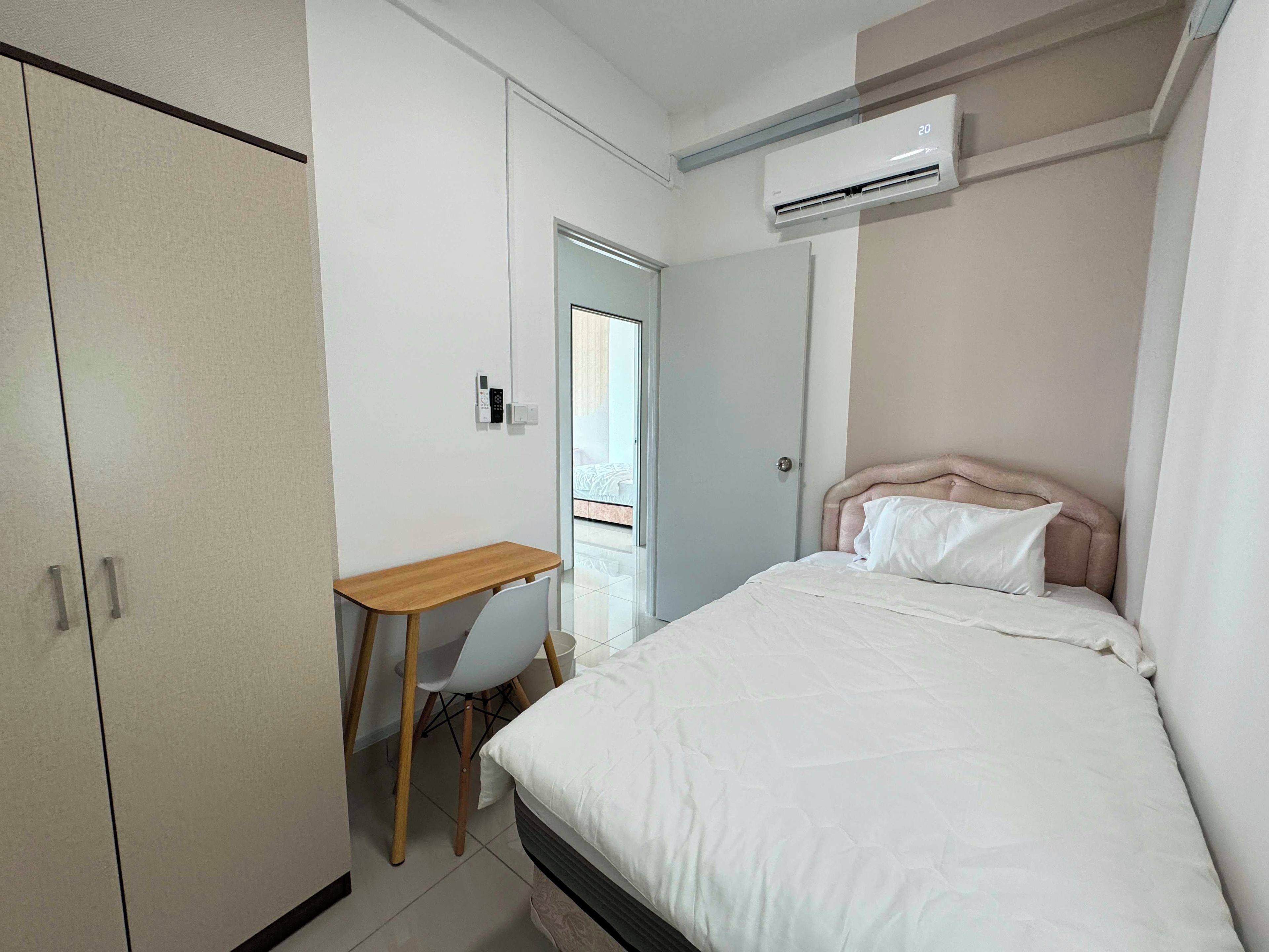 A bedroom with a bed, a desk, and a wardrobe.