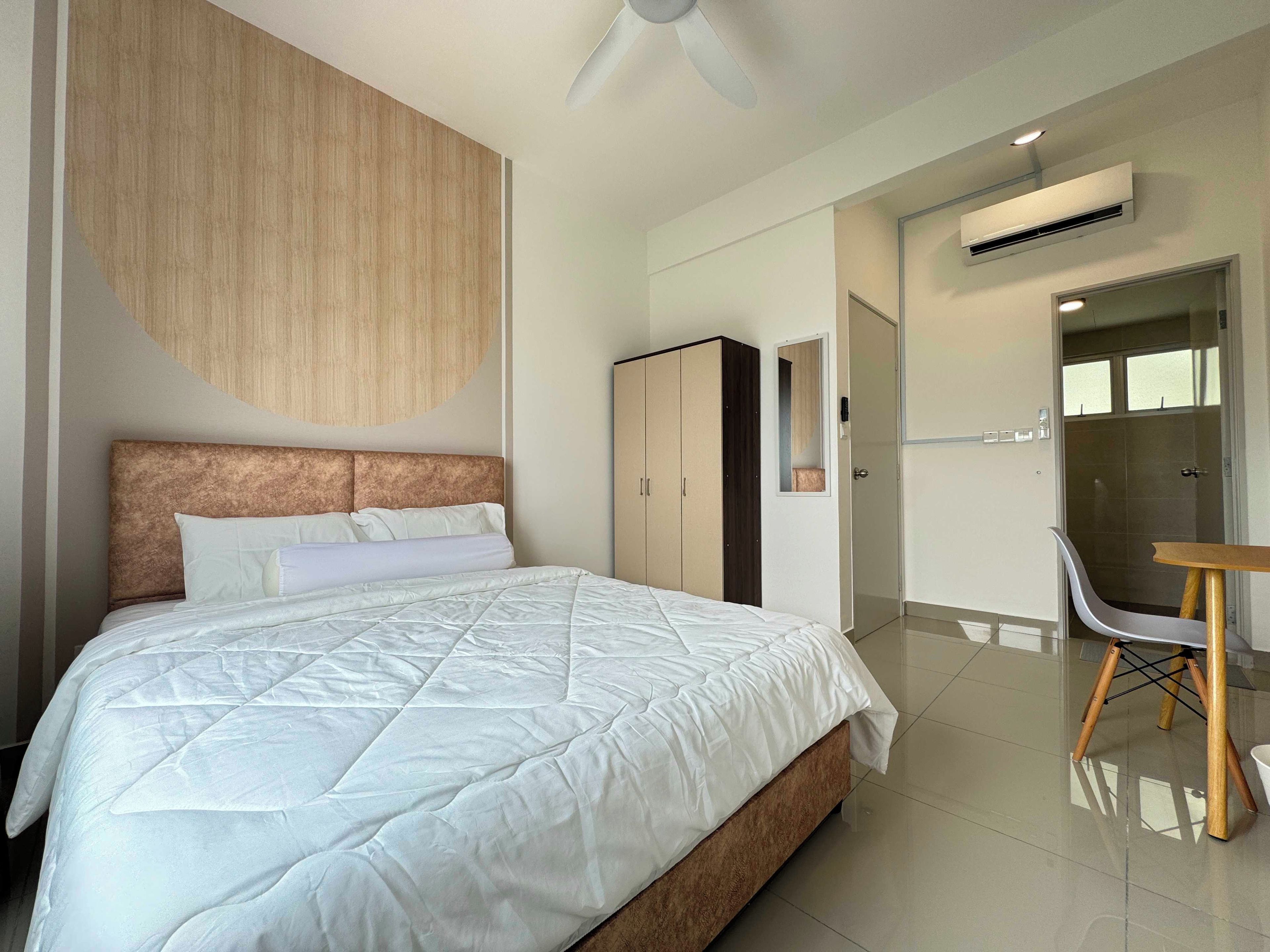 A modern hotel room with a large bed, a wardrobe, a desk, and a shower area.