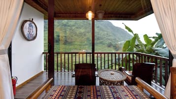 A balcony with a patterned floor, wooden furniture, and a view of a mountainous landscape.