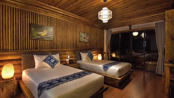 A room with two beds, wooden paneling, a painting, and a chandelier.