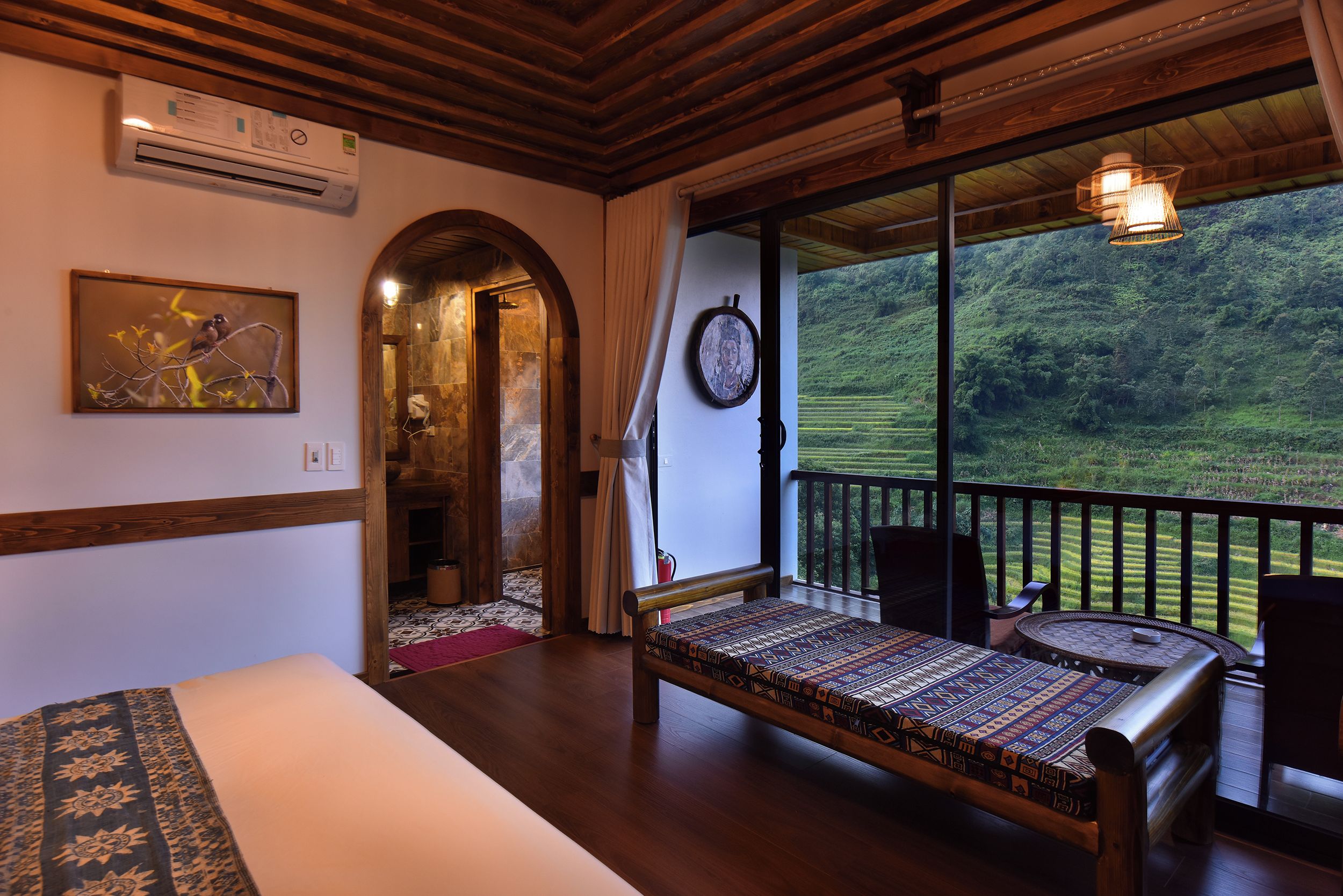 Ein Zimmer mit einem Bett, einem Esstisch und Blick auf eine üppige grüne Landschaft.