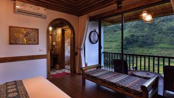 Ein Zimmer mit einem Bett, einem Esstisch und Blick auf eine üppige grüne Landschaft.