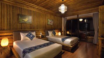 A hotel room with two beds, wooden paneling, a chandelier, and a large window with curtains.