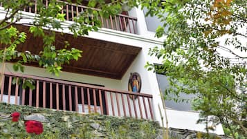 Un immeuble à plusieurs étages doté d’un balcon, d’un mur en pierre et d’une fresque murale.