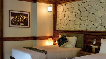 Une chambre d’hôtel avec un lit, une table de chevet, une lampe, un tableau encadré et un mur en pierre.