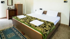Habitació d'hotel amb un llit, un ventilador de sostre, una taula de nit, un mirall i una catifes.