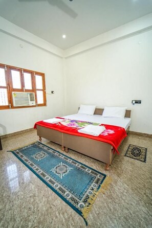 Una camera da letto con un letto, una finestra, un condizionatore d'aria a parete e un tappeto decorato.